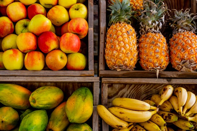 Apples, pineapple, mango and banana bunches on display at a market